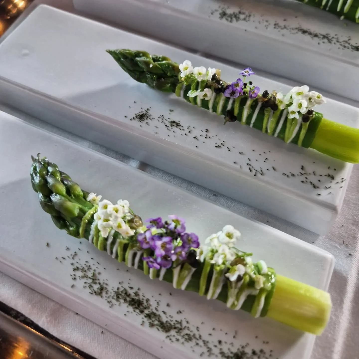 Asperges garnies d'herbes et de fleurs sur un plateau blanc