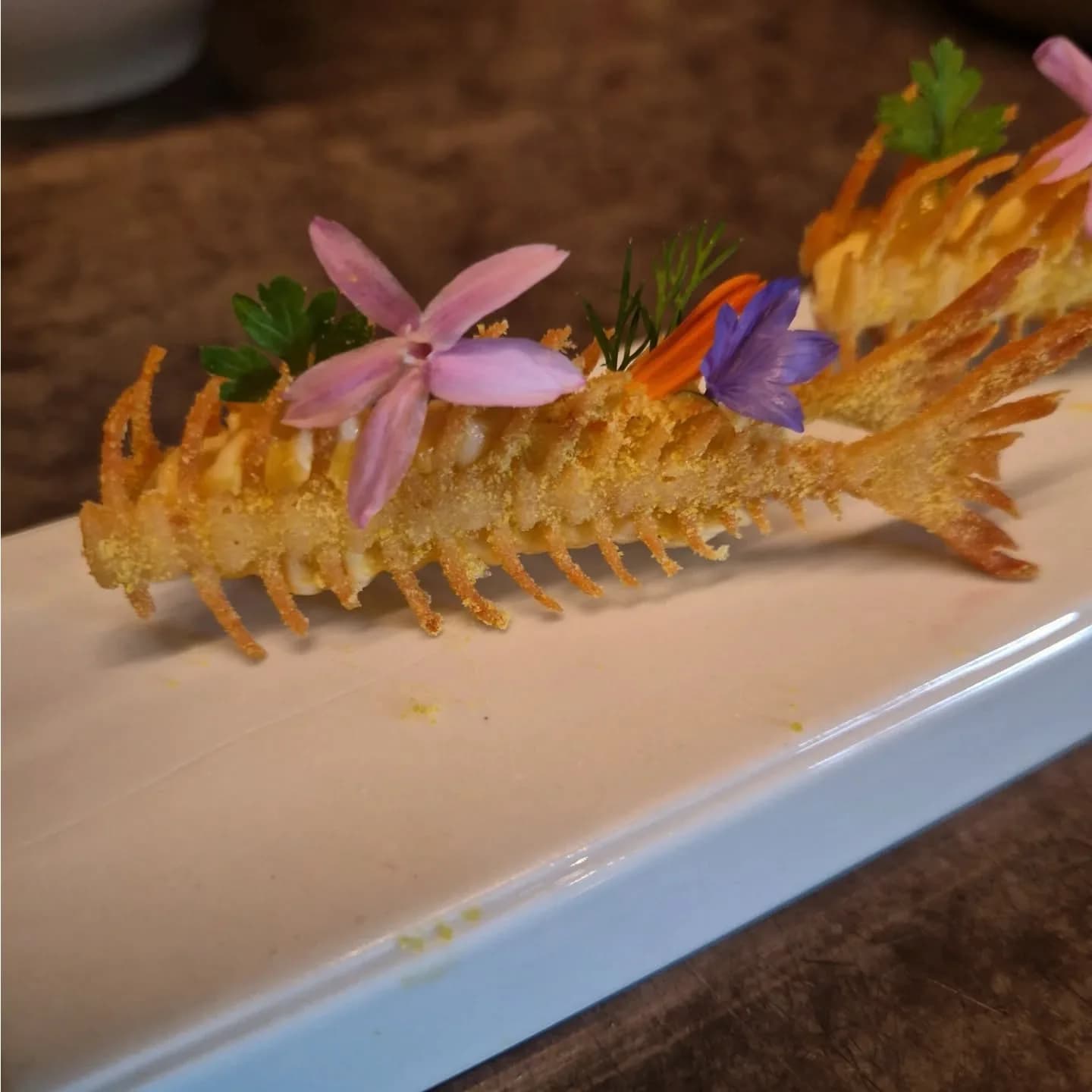 Une queue de langoustine croustillante garnie de fleurs comestibles