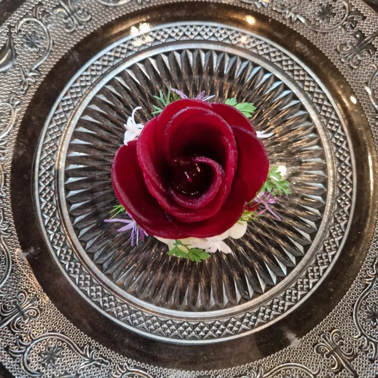 Une rose comestible présentée sur un plat d'argent gravé